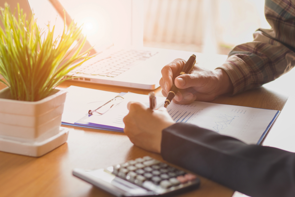 A person reviewing financial figures on a report with a calculator