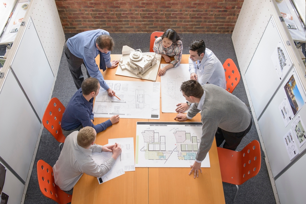 A team reviewing project plans and blueprints around a table