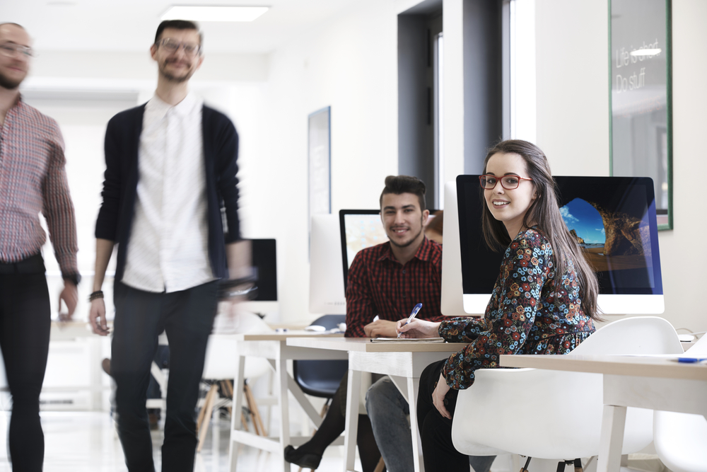 Open-plan office with team members working at desks and moving between them