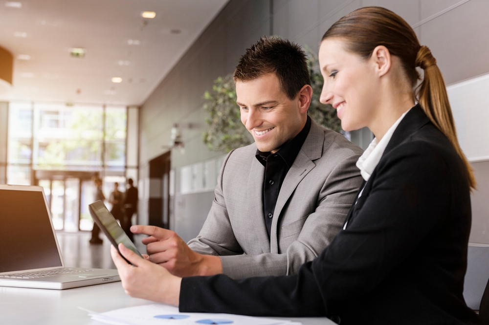 Two colleagues reviewing work together on a tablet in an office
