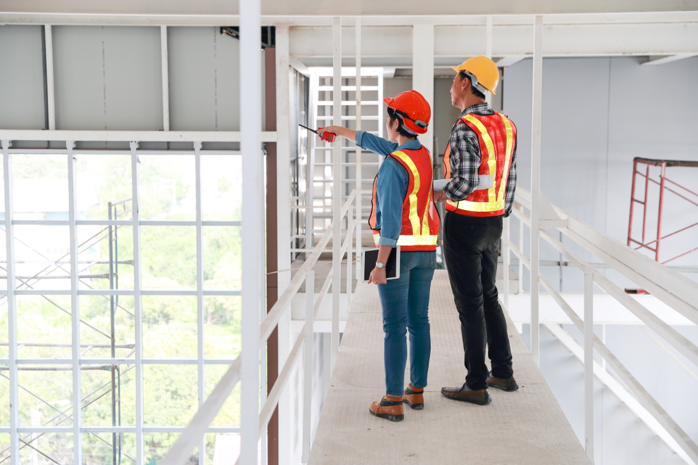 Two workers in safety vests and hard hats inspecting a distribution facility