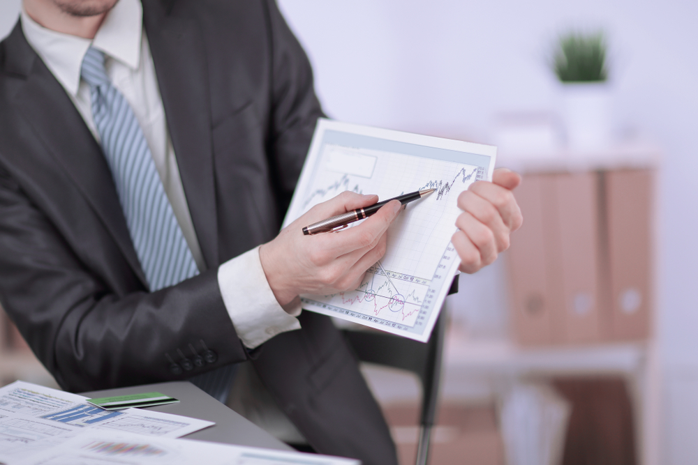 A business leader reviewing a performance chart with a pen at a desk