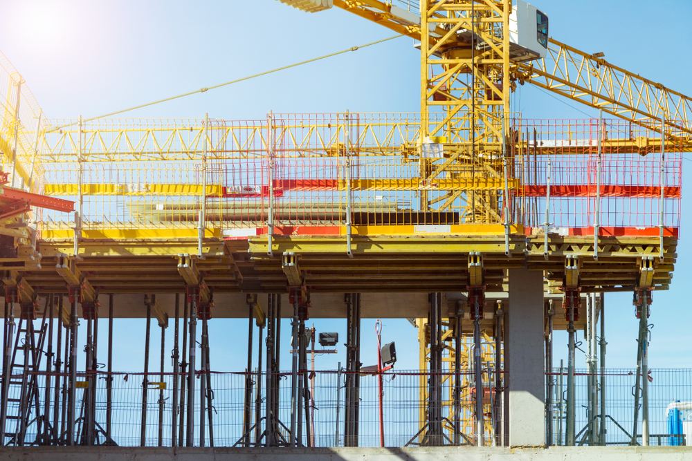 A large construction structure with cranes and scaffolding against a clear sky, representing operational restructuring