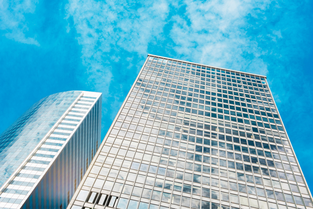 Office towers rising against a clear blue sky, viewed from below