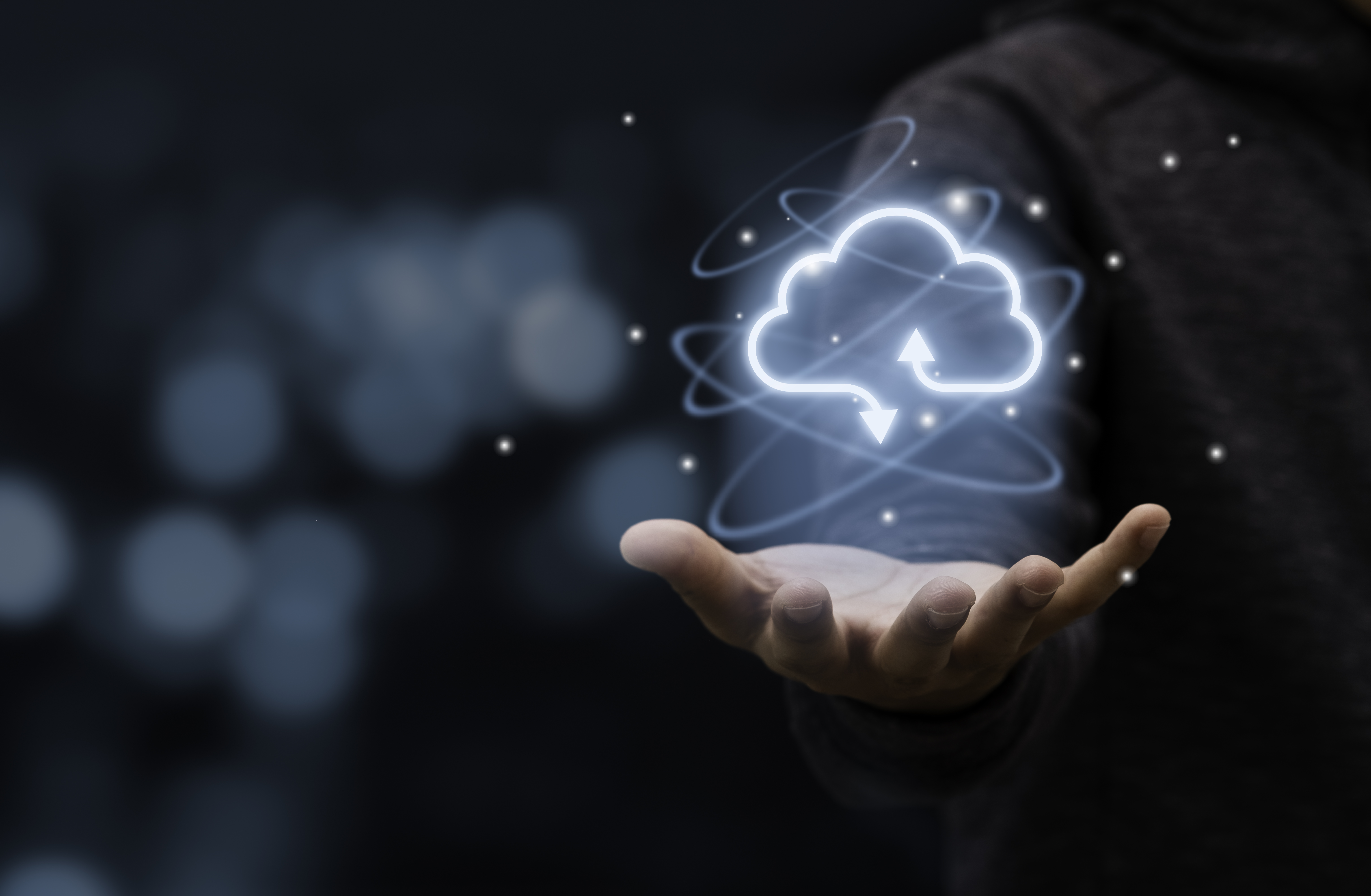 Person's hand extended with glowing cloud icon symbolizing cloud computing and data transfer.