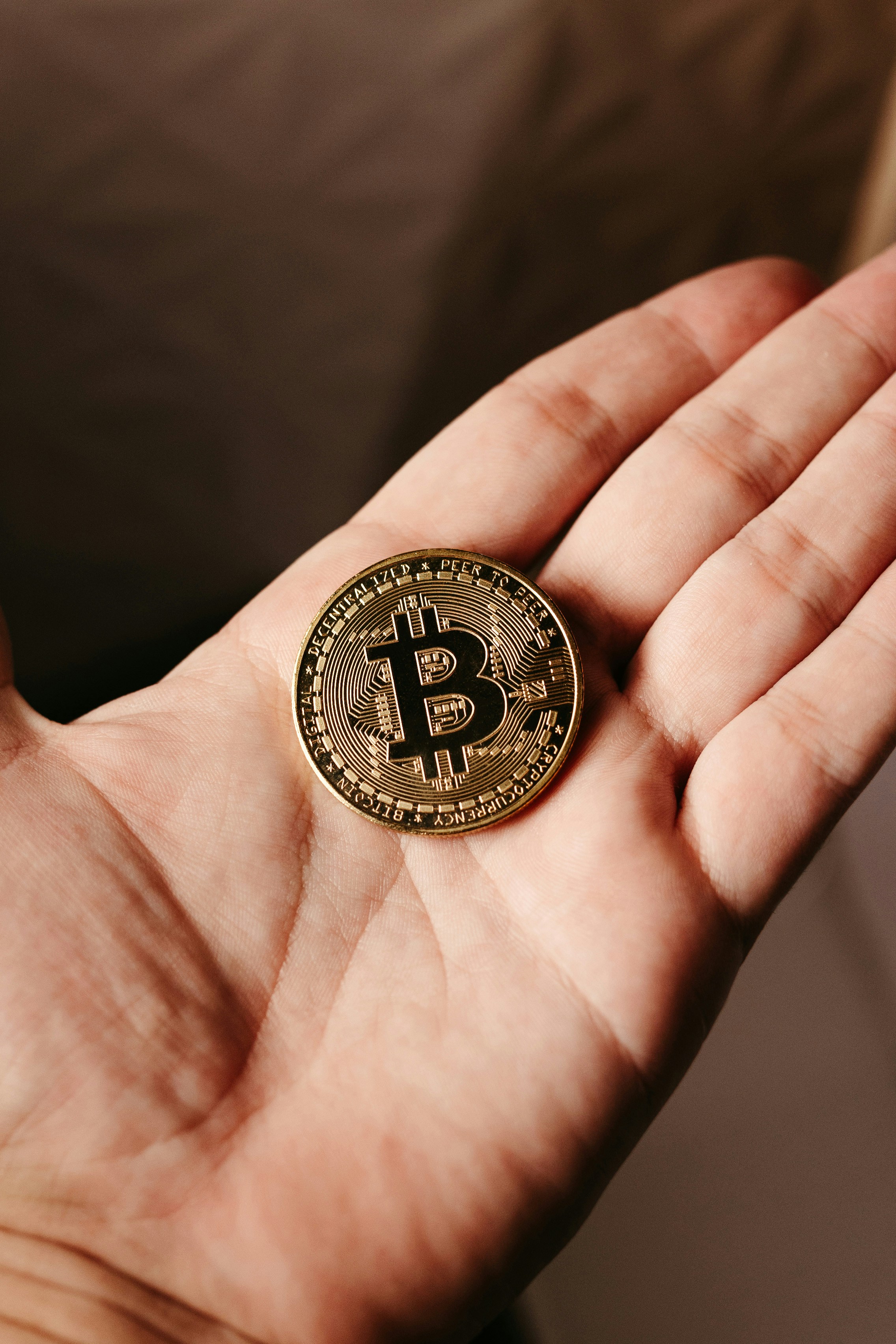 Close-up of an open hand holding a gold Bitcoin coin.
