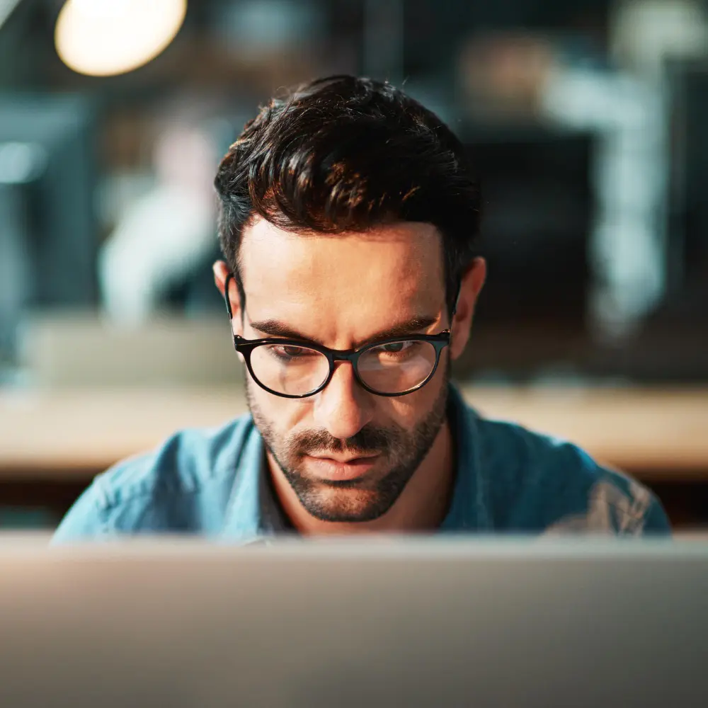 Man in plaid shirt plugging an Ethernet cable into the back of a desktop computer.