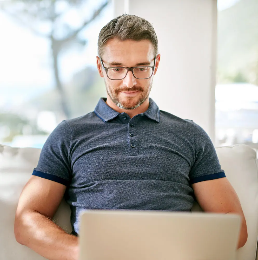 Man in plaid shirt plugging an Ethernet cable into the back of a desktop computer.