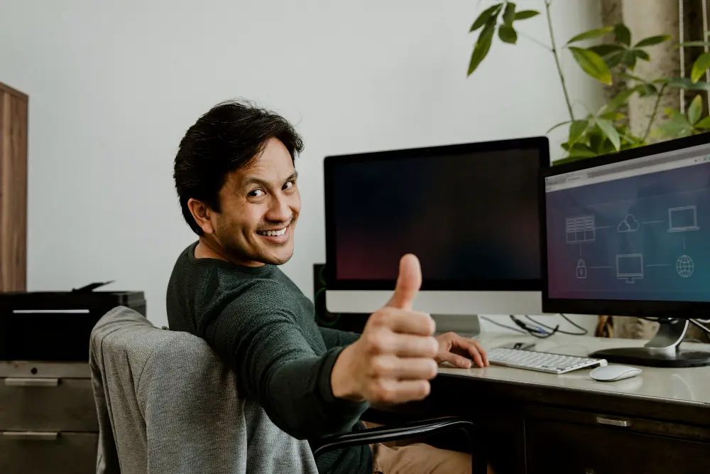 Man in plaid shirt plugging an Ethernet cable into the back of a desktop computer.