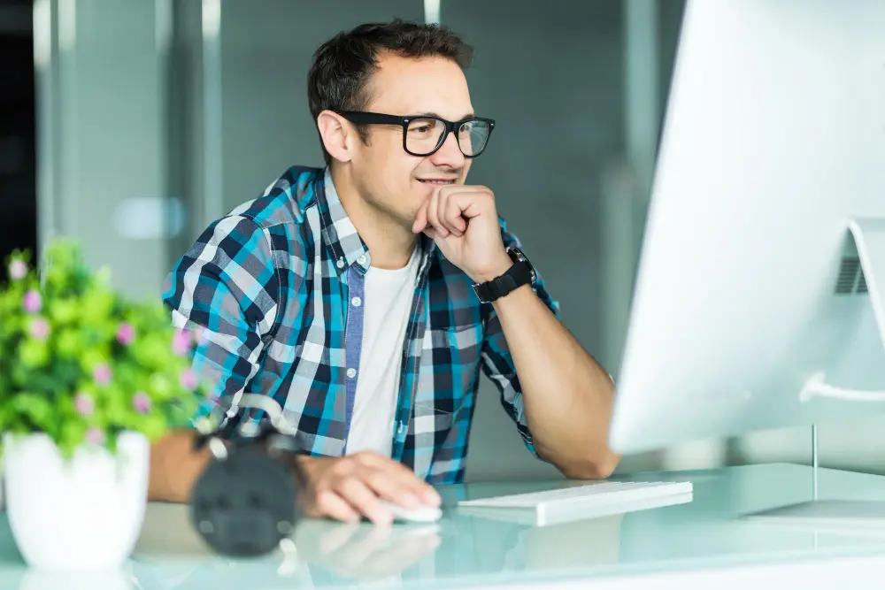 Man in plaid shirt plugging an Ethernet cable into the back of a desktop computer.