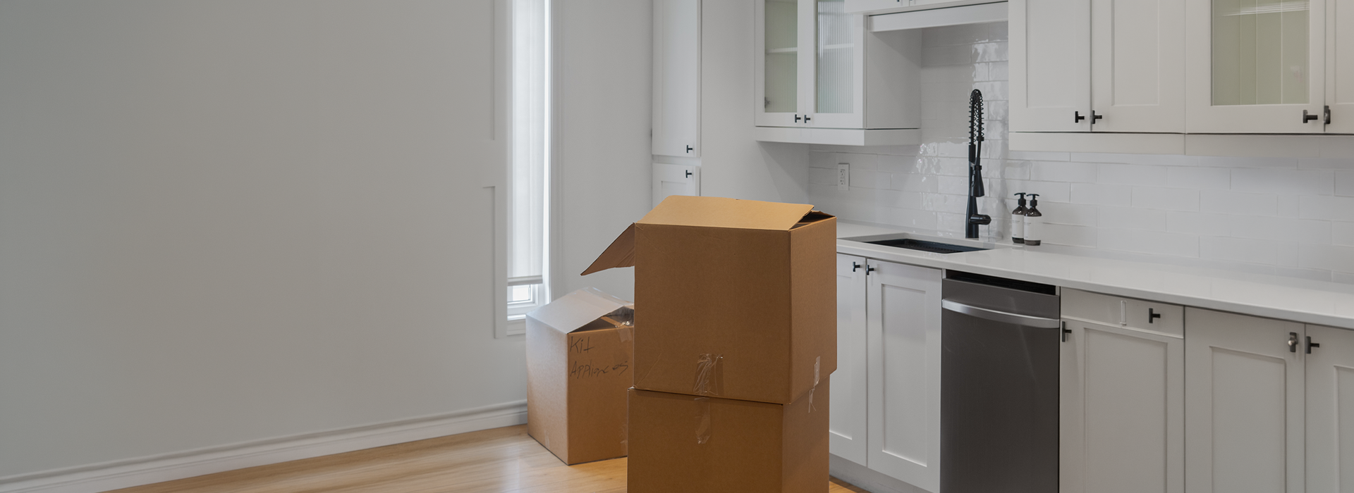 Stacked cardboard boxes in an empty kitchen, packed and ready to move