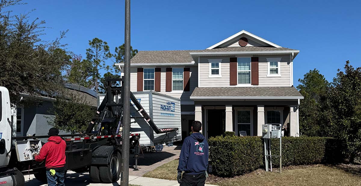 We Got Moves crew member in front of a two-story home as a truck handles a portable storage container