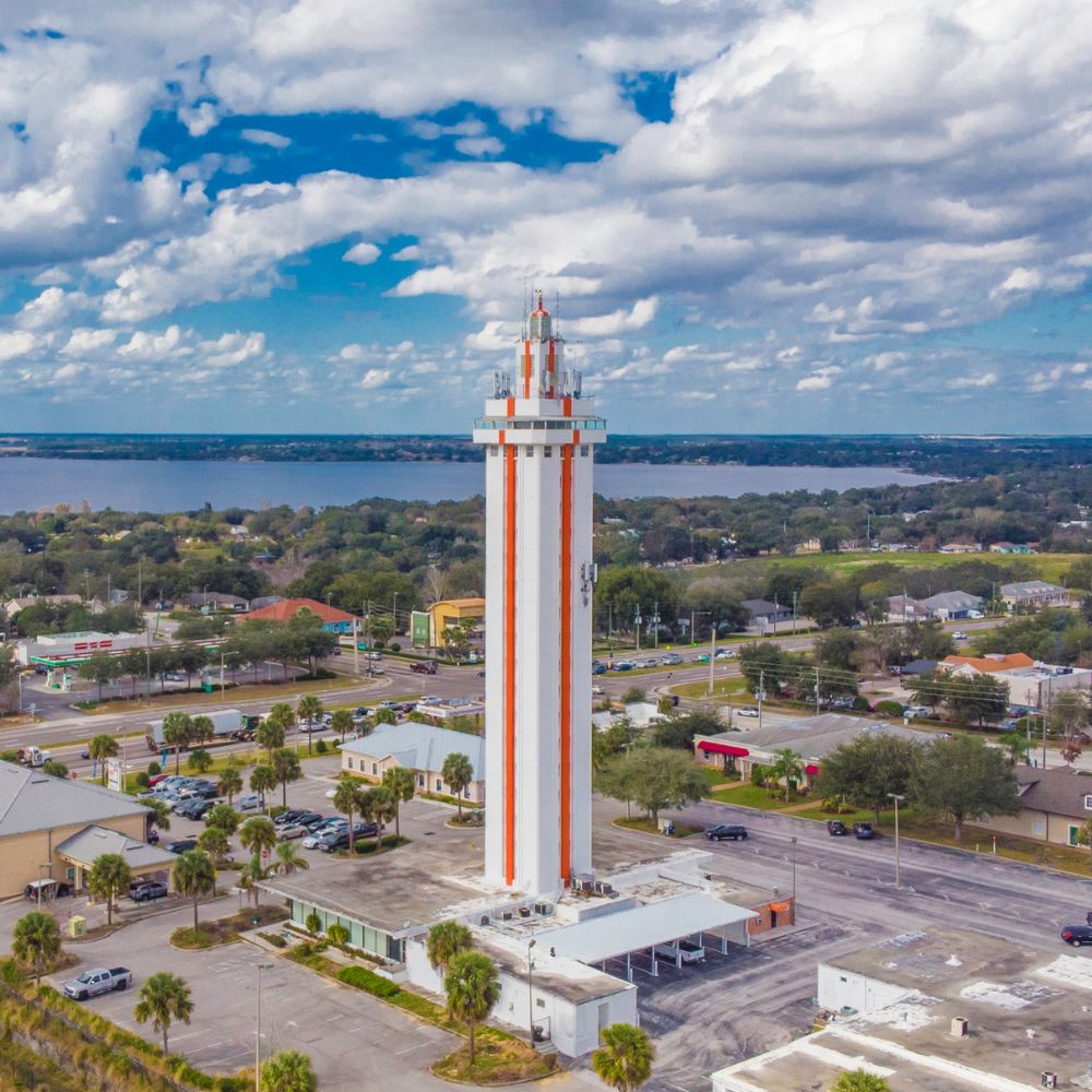 Clermont Citrus Tower, white with orange stripes, rising above the town with a lake behind it