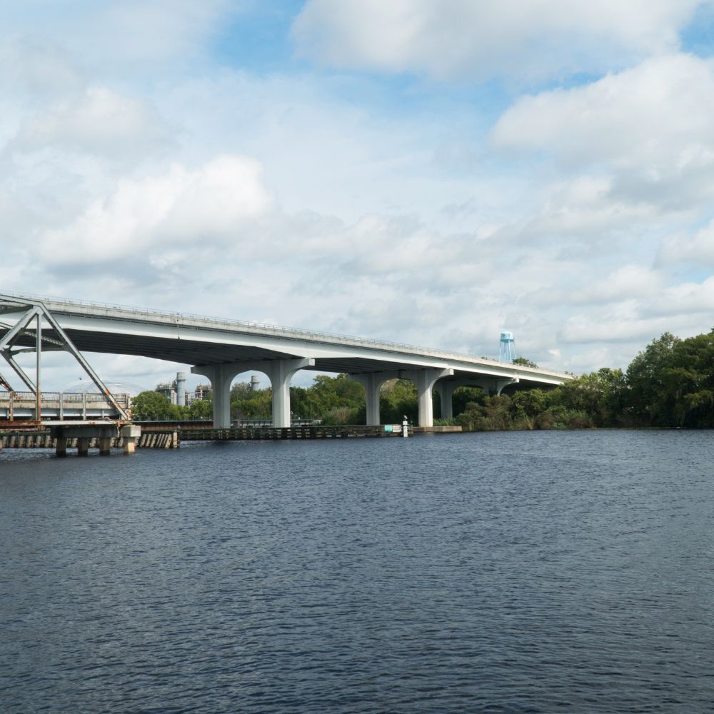 Concrete bridge crossing a river under a cloudy sky