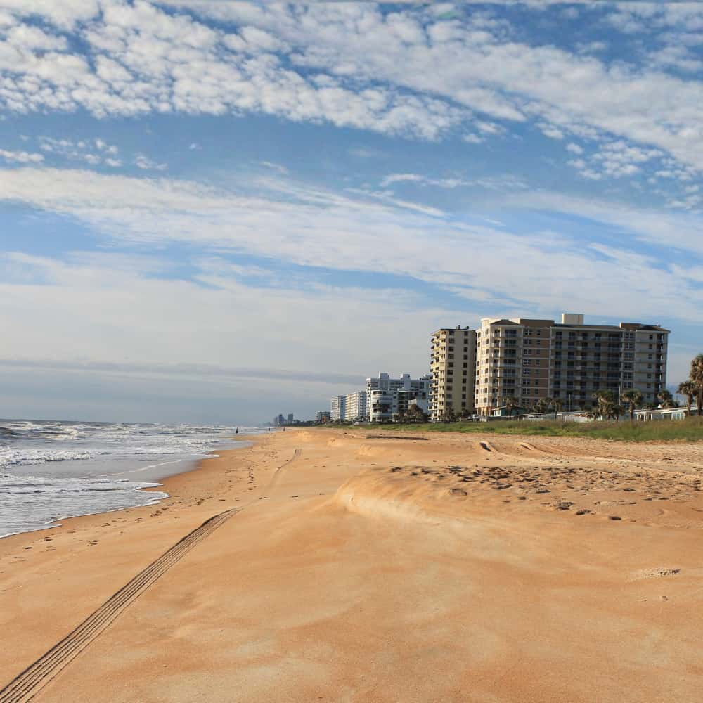 Beach with oceanfront condo towers and tire tracks in the sand