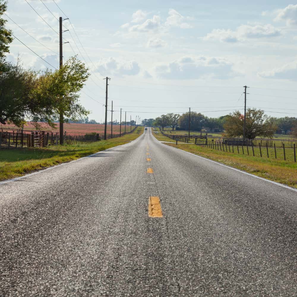 Two-lane country road with fence lines and open pasture in Central Florida