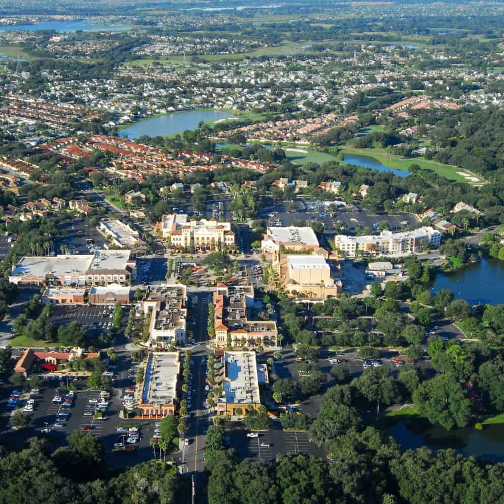 Aerial view of a town center in The Villages, Florida, with shops, a pond, and a golf course