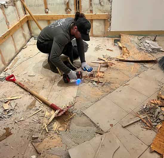 Worker pulling up old flooring during a small demolition project