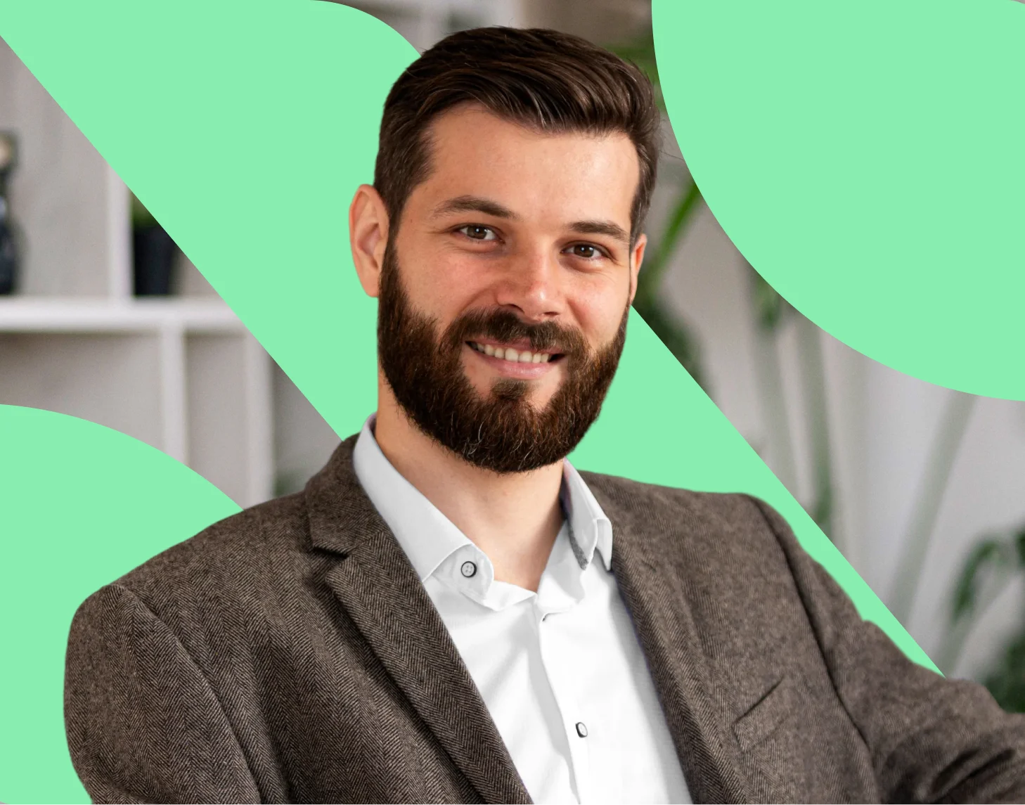Smiling man with brown hair and beard wearing a brown blazer and white shirt, with a green abstract background.