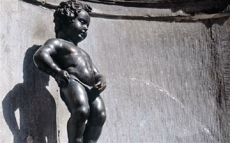 Bronze statue of a small boy urinating, known as Manneken Pis, with water arcing from him in a fountain.
