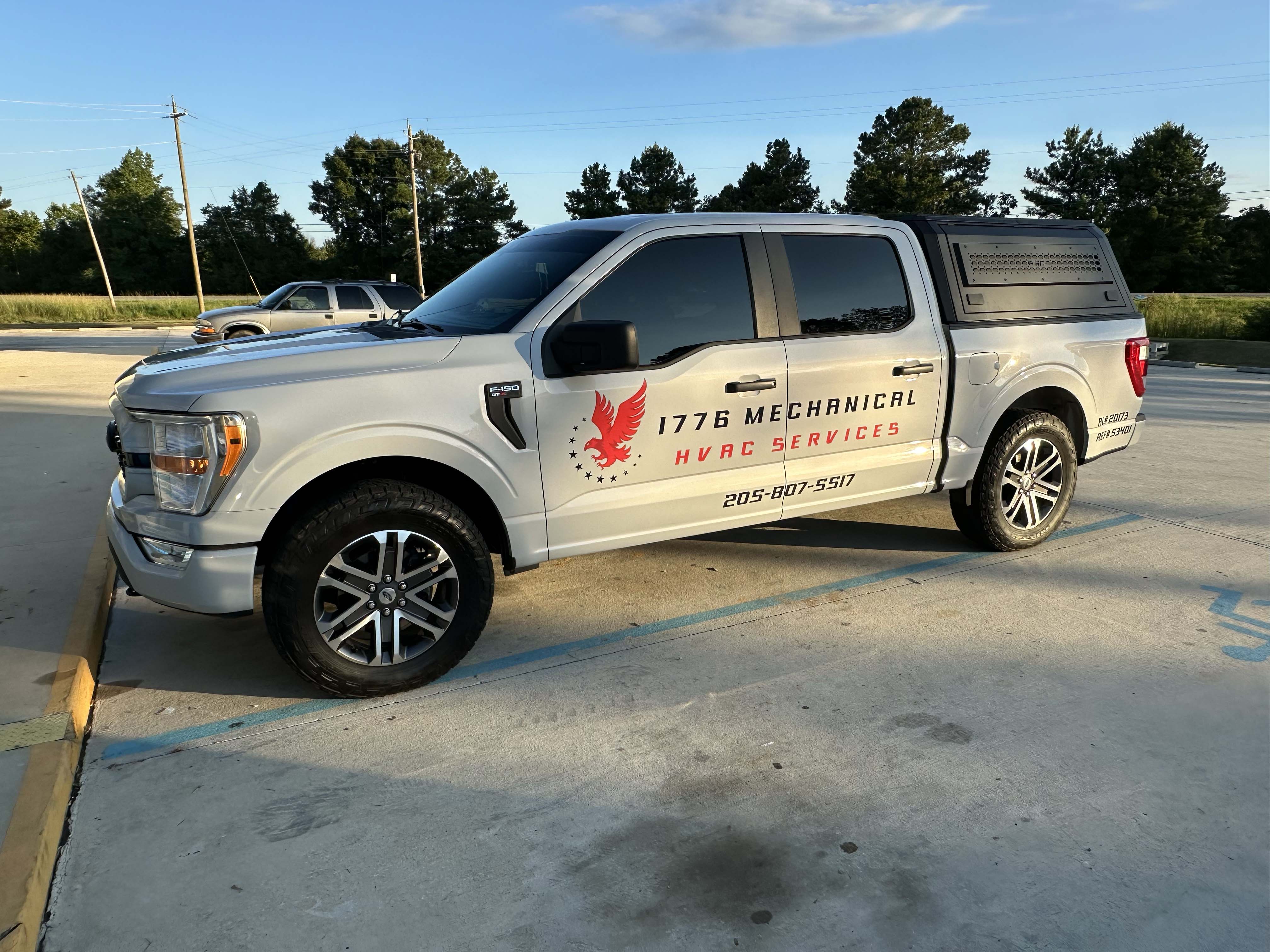 Silver Ford F-150 pickup truck with 1776 Mechanical HVAC Services branding parked in a lot.