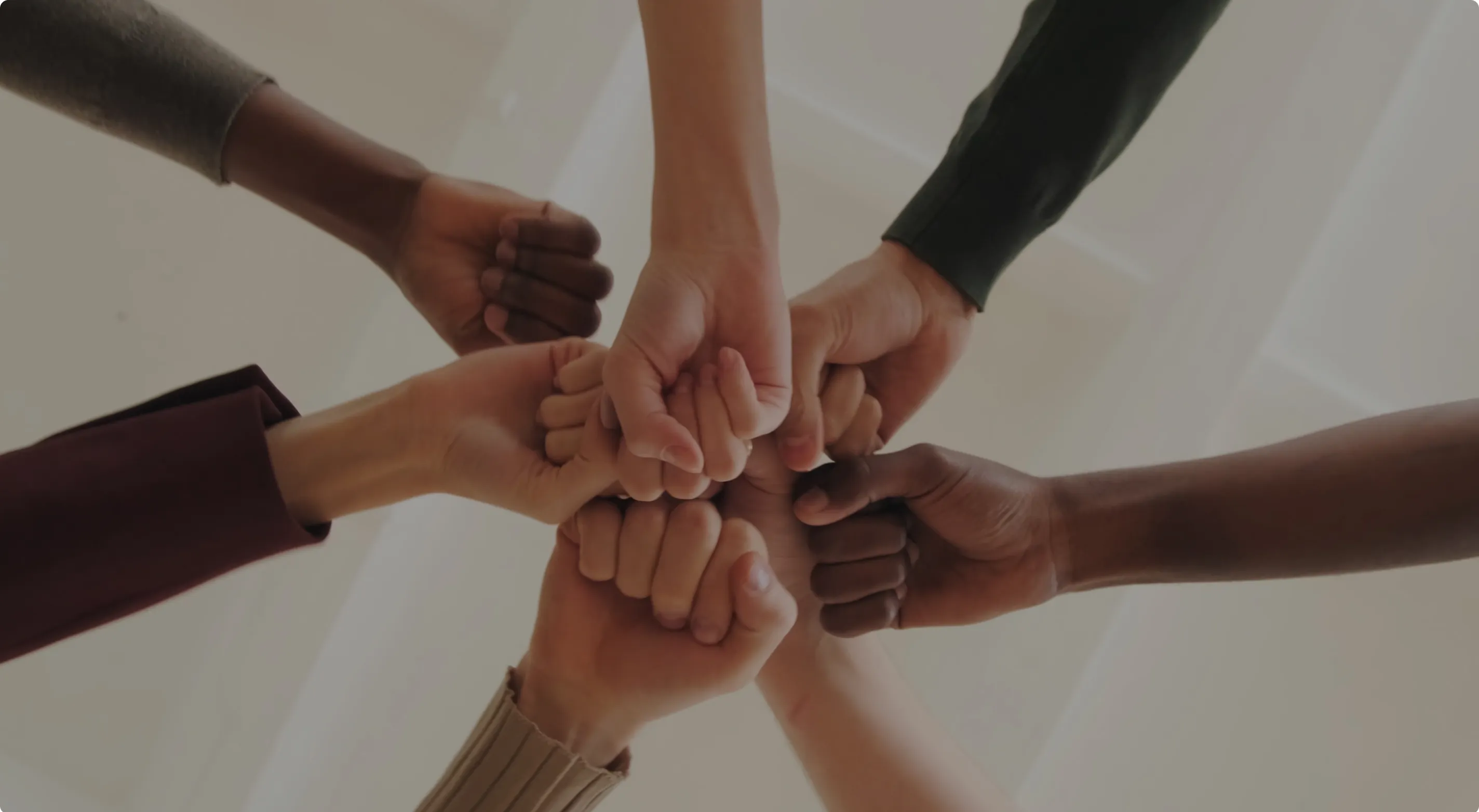 Plusieurs mains de différentes personnes serrant les poings ensemble en signe d'unité.