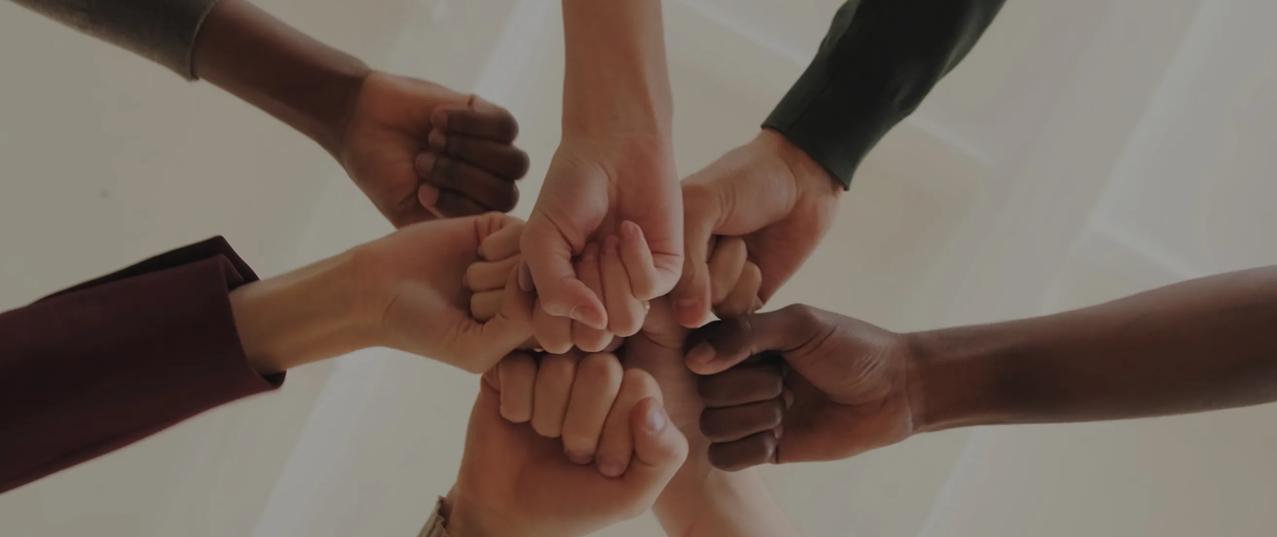 Un groupe de poings serrés de différentes personnes réunis au centre en signe d'unité.