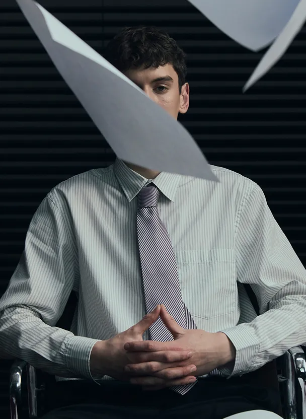 Homme d'affaires pensif assis avec des documents volants devant lui.