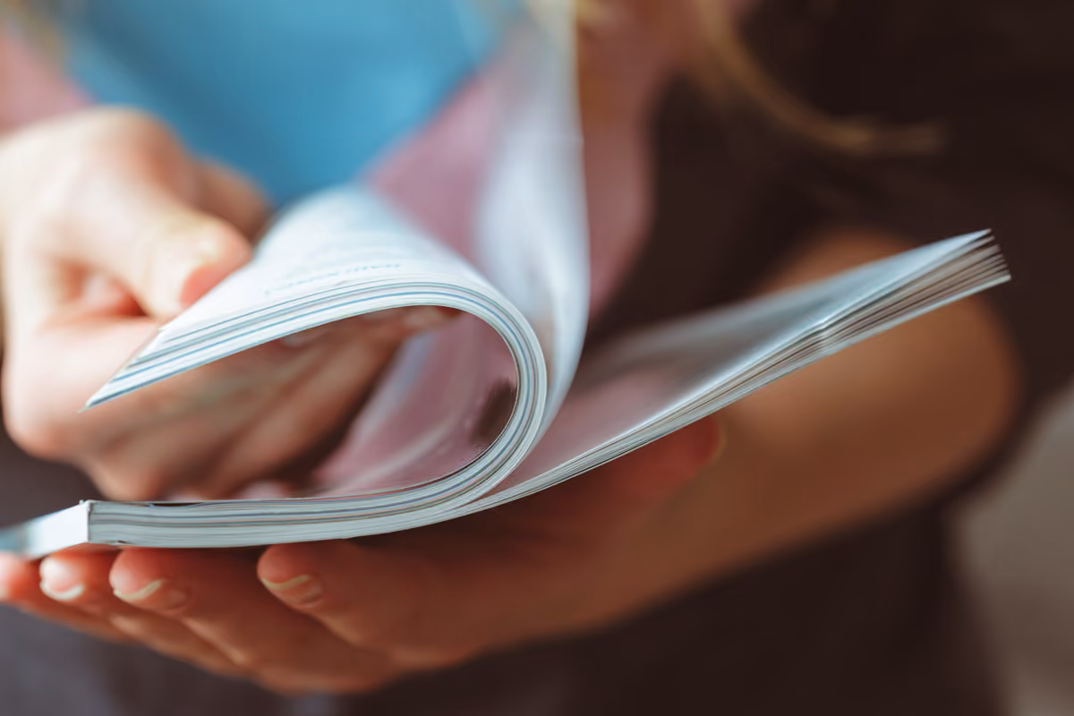 Person flipping through pages of a booklet or magazine.