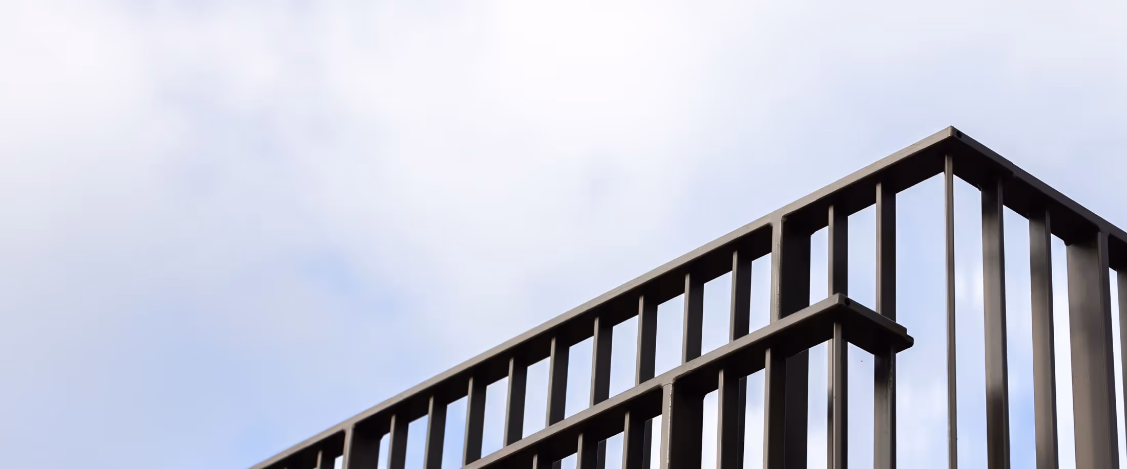 Et metalhegn med en blå himmel i baggrunden.