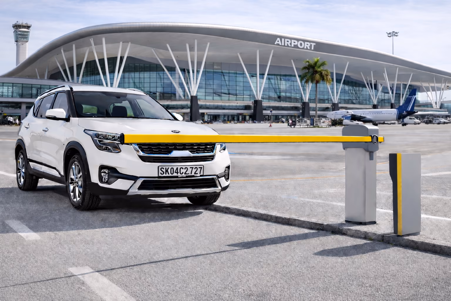 White SUV stopped at a yellow airport parking barrier in front of a modern airport terminal with an airplane and control tower visible.