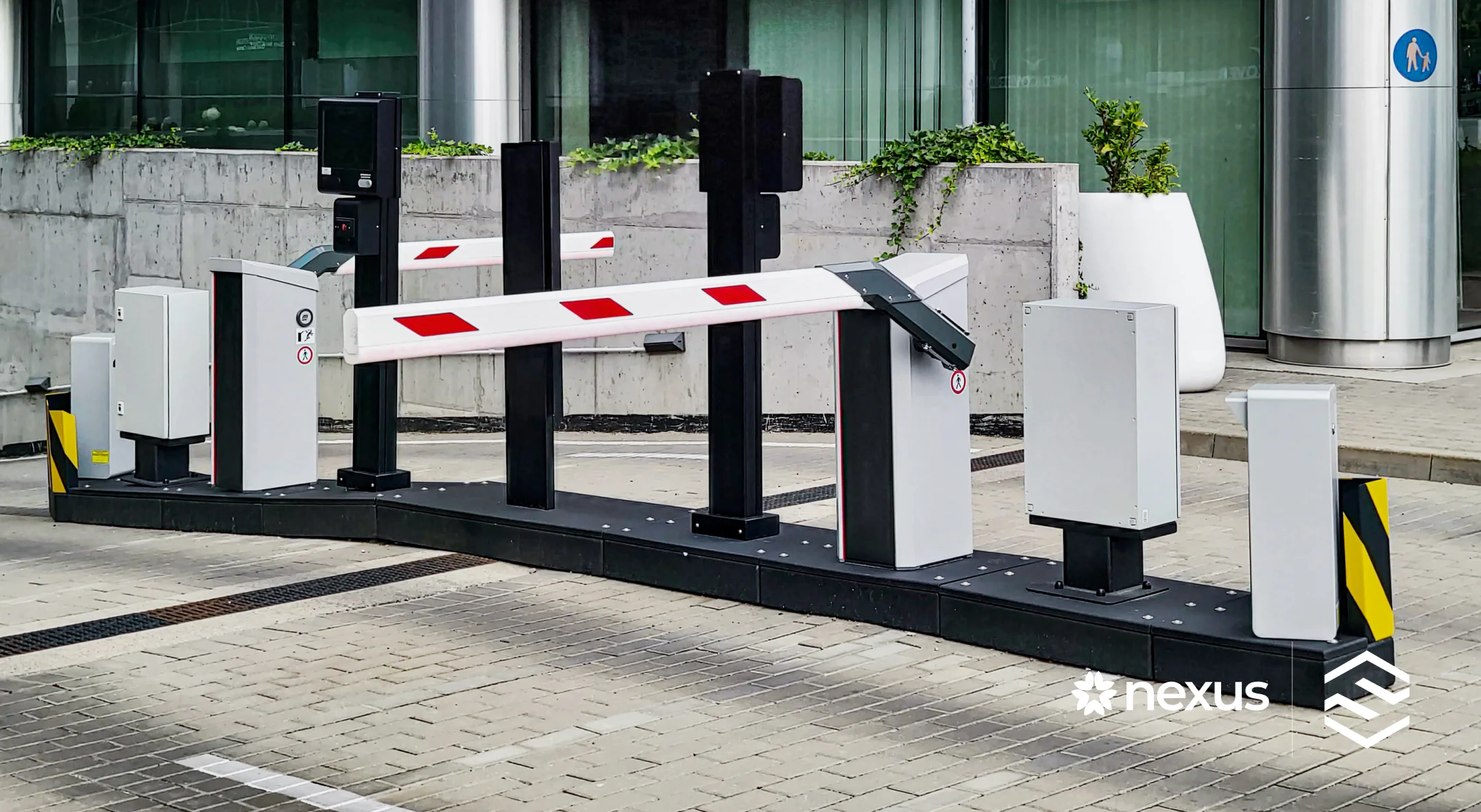 Modern automated parking barrier system with white and red striped barriers on paved ground.