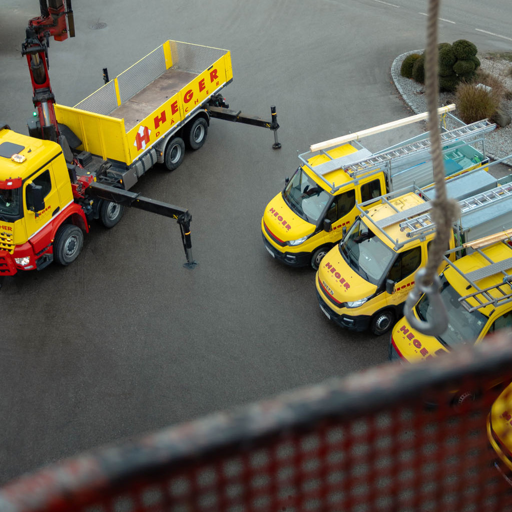 Gelbe LKW und Transporter der Firma Heger auf einem Parkplatz, von oben aufgenommen.