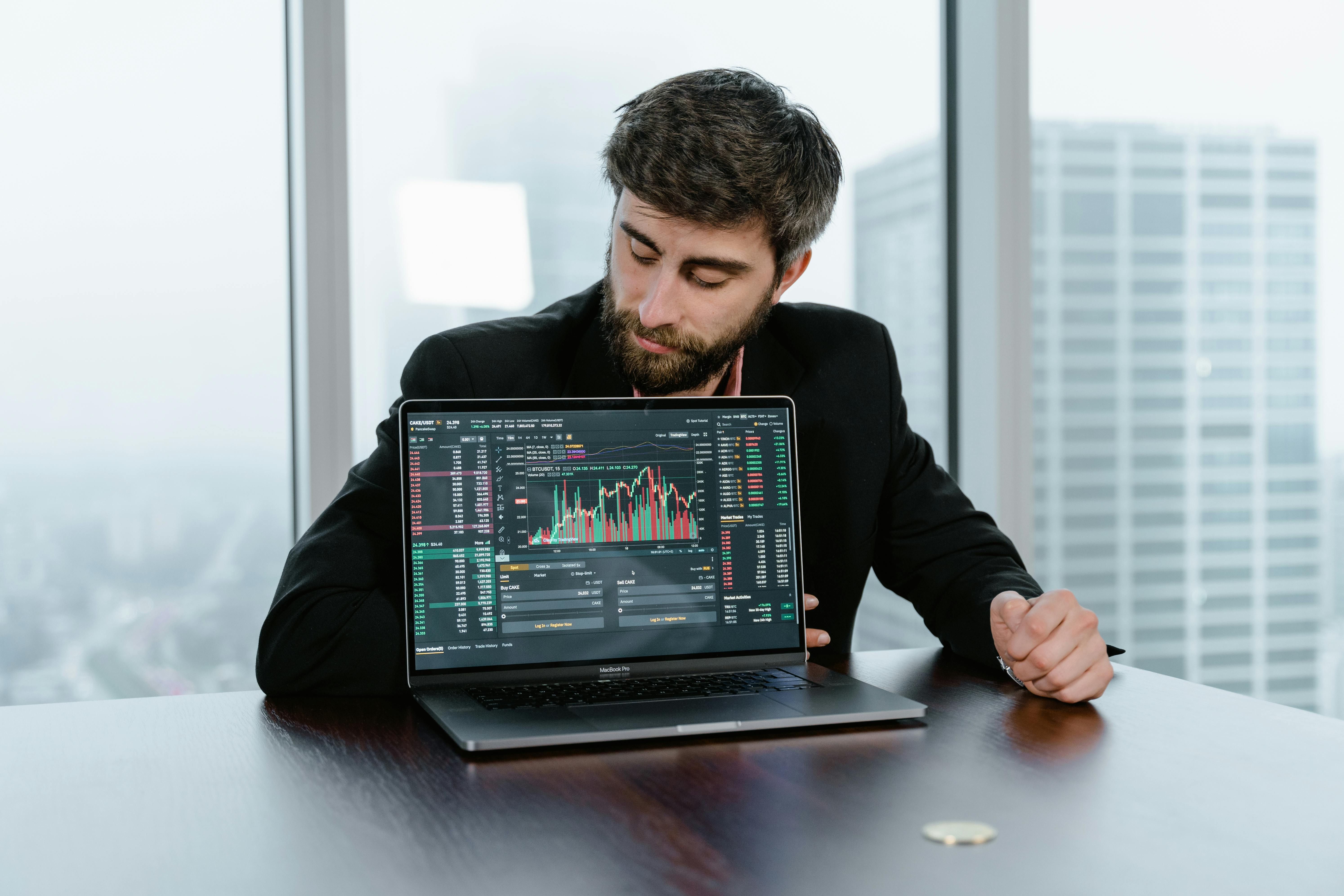 A Man in Black Suit Looking at the Laptop on the Table - What Is a Fair Value Gap in Trading