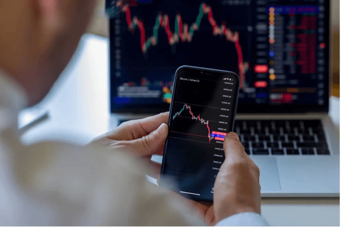  Man monitoring financial charts on devices - Volatility Trading