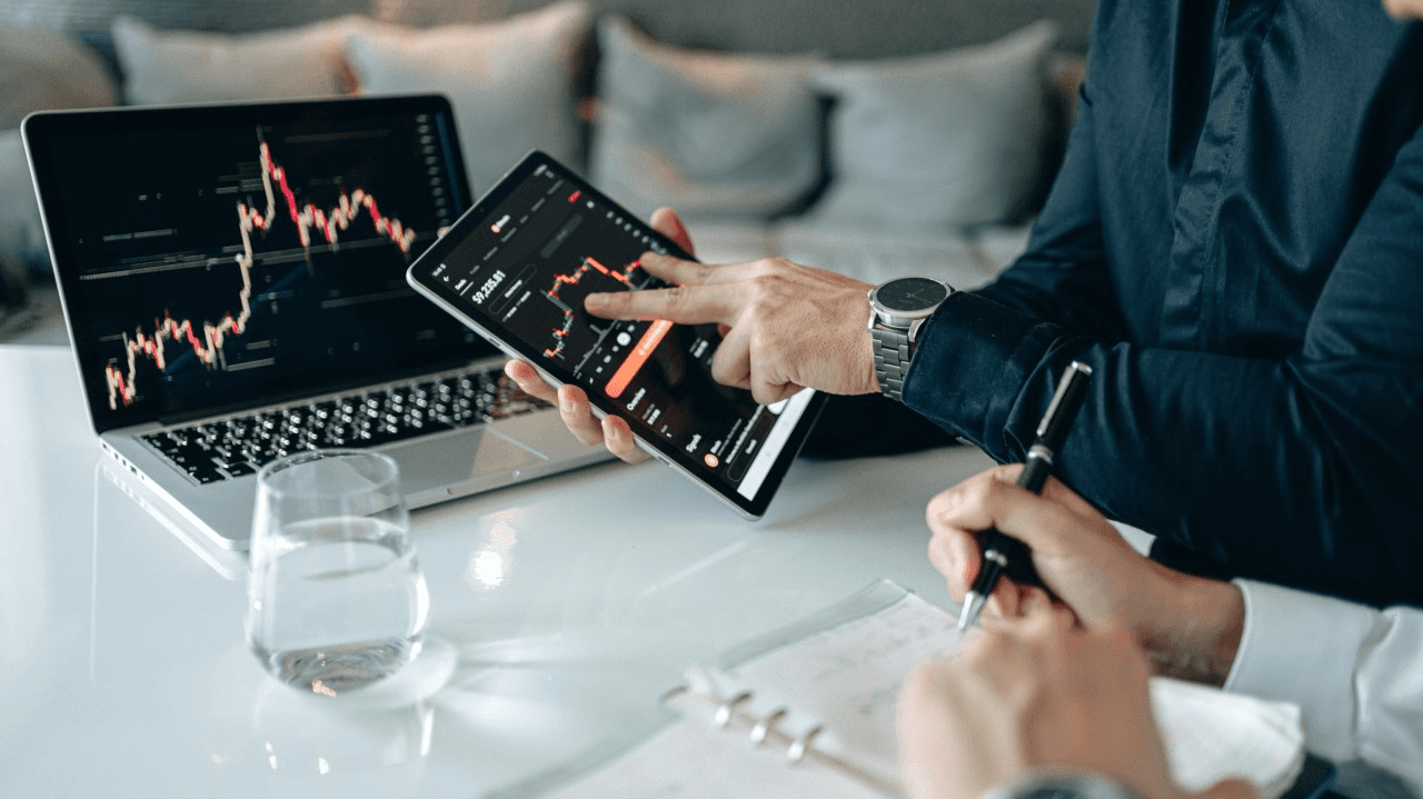 People analyzing financial charts on screens -  Basic Trading Strategy
