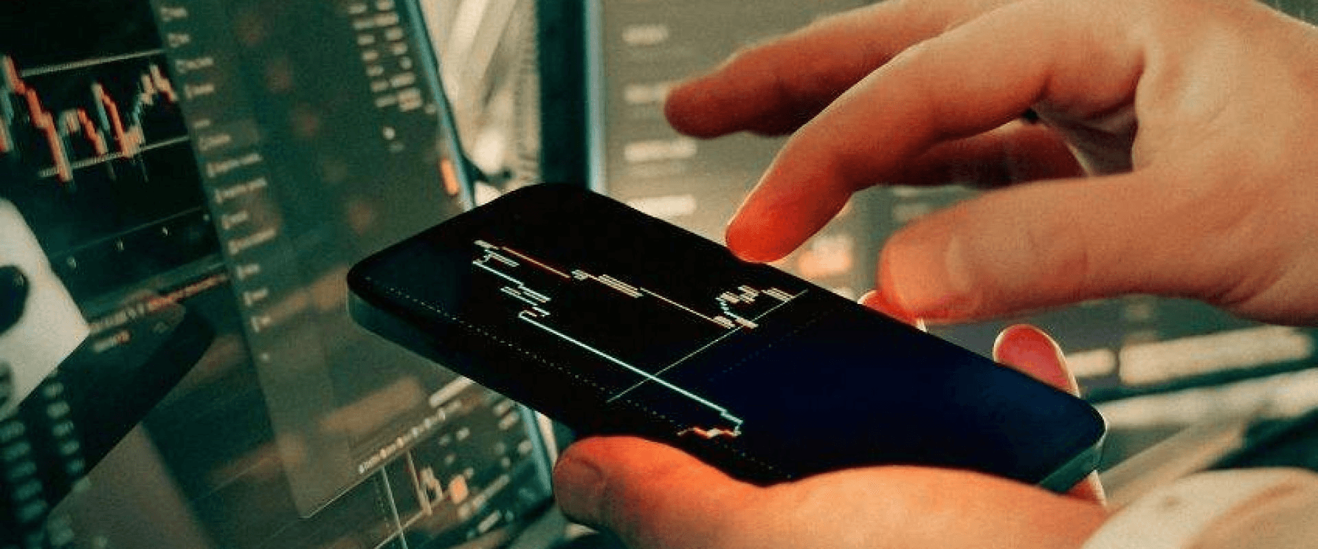 Hand analyzing trading charts on smartphone - Futures Trading For Beginners