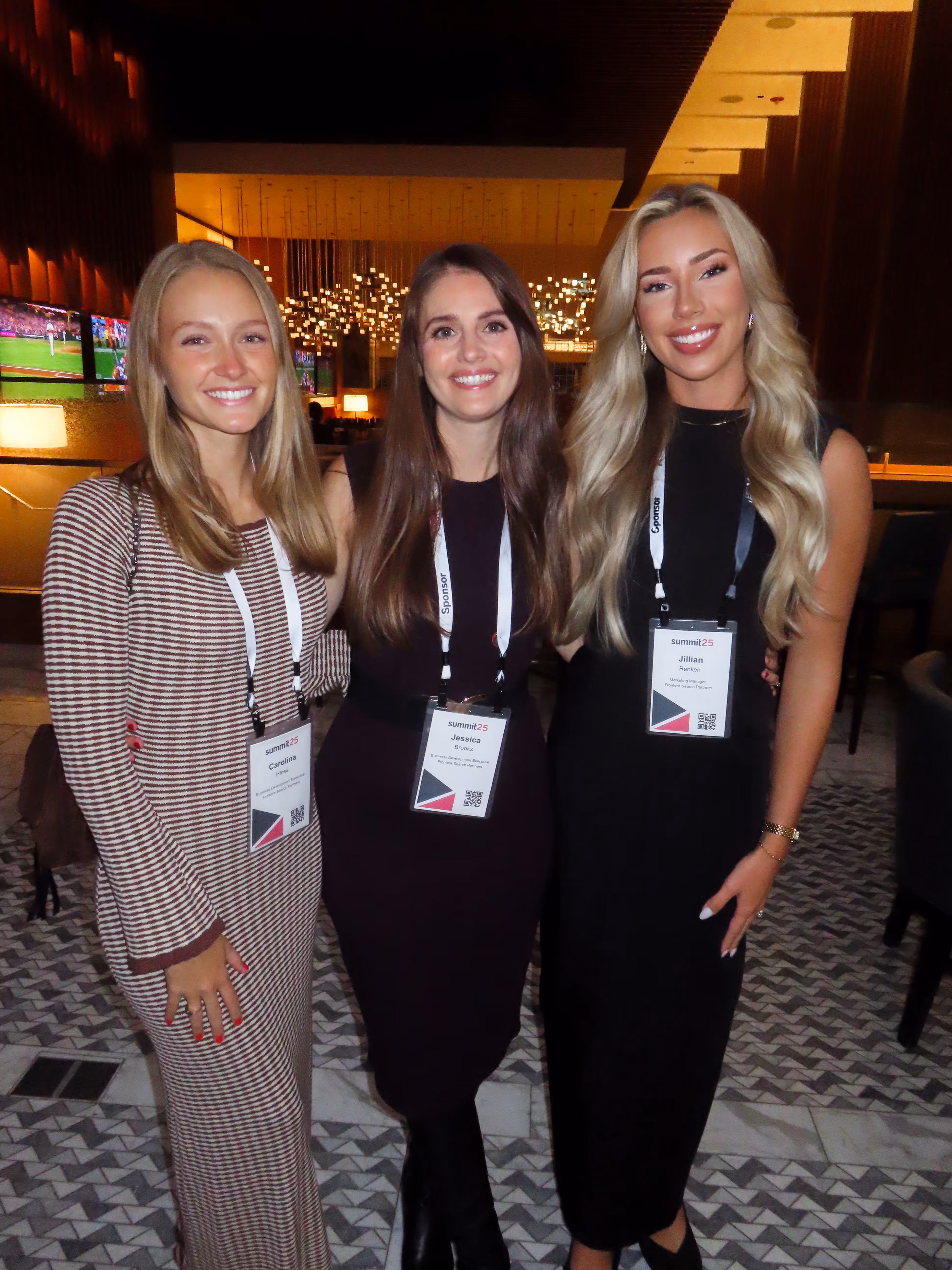 Three smiling women wearing conference badges networking at a professional healthcare or staffing industry event, representing collaboration and partnerships.