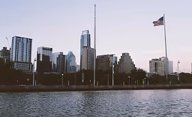 Austin skyline at dusk with buildings, waterfront, and an American flag, representing Texas’s growing healthcare, technology, and staffing market.