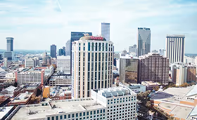 Downtown cityscape with high-rise buildings under a partly cloudy sky, representing a metropolitan area with healthcare facilities and workforce demand.