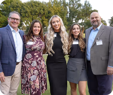 Five professionals standing outdoors in business casual attire, representing team collaboration and professional networking.
