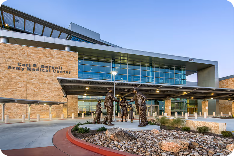 Carl R. Darnall Army Medical Center building with a bronze statue of five people shaking hands outside.