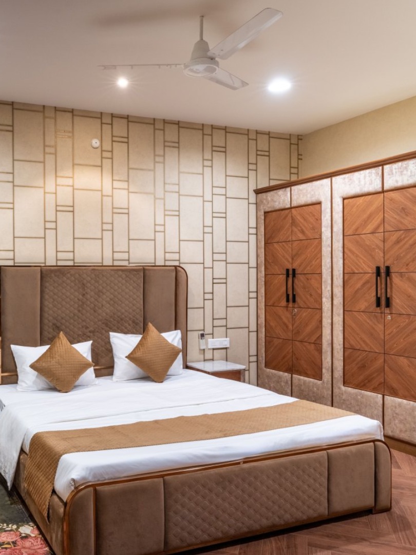 A beautifully decorated outdoor wedding mandap at Sri Narayana Vanam farmhouse, featuring elegant white floral arrangements, gold-toned drapes, and hanging crystal chandeliers. The ceremony is taking place on a raised platform set upon a lush green party lawn, with rows of gold Tiffany chairs arranged for guests at Survey number 129, Moinabad Mandal, Aziznagar, Hyderabad, Telangana 500075. This premium venue is perfect for intimate farm stay weddings and traditional celebrations.