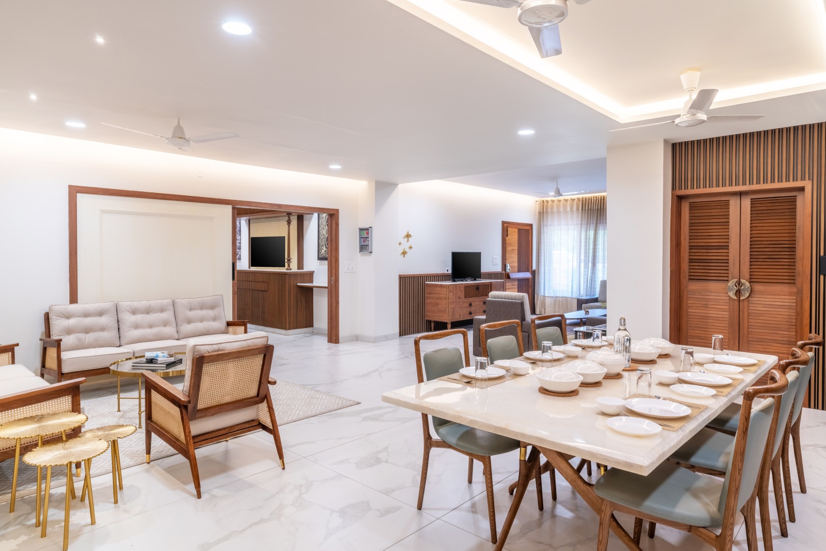 Luxury open-plan living and dining hall at Sri Narayana Vanam farmhouse in Moinabad, Hyderabad, featuring a large marble dining table, contemporary sofa seating, and elegant white interiors at Survey number 129, Aziznagar, Telangana 500075.