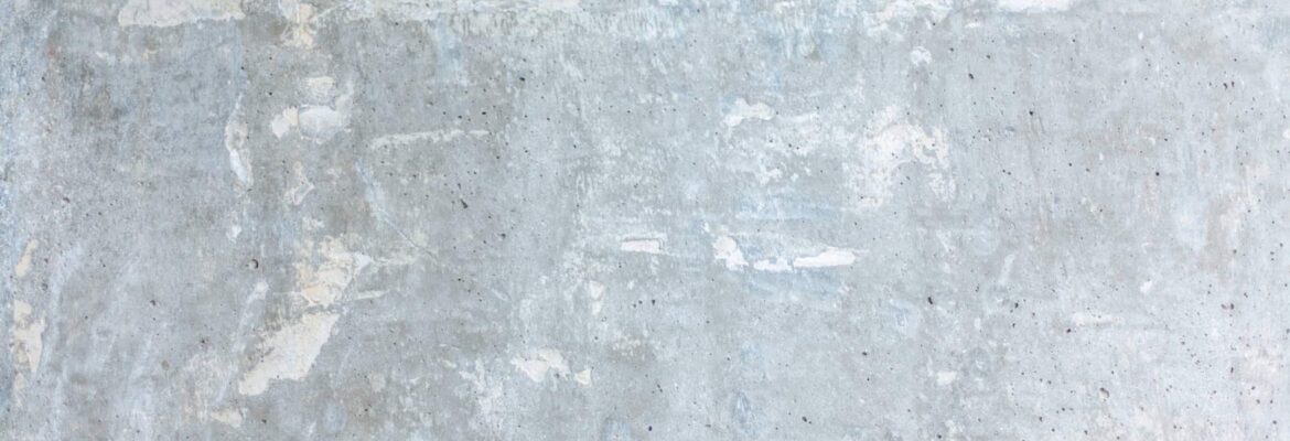 Surface de béton gris clair avec des taches et marbrures blanchâtres irrégulières.