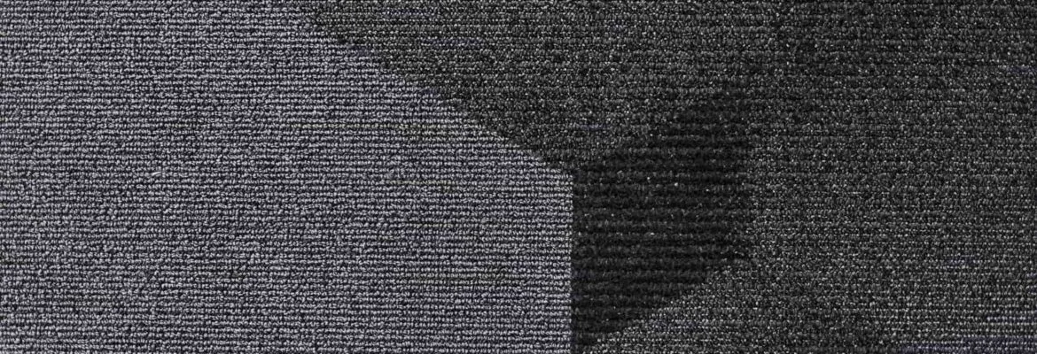 Carpette à poils ras avec un motif géométrique en nuances de gris et noir.