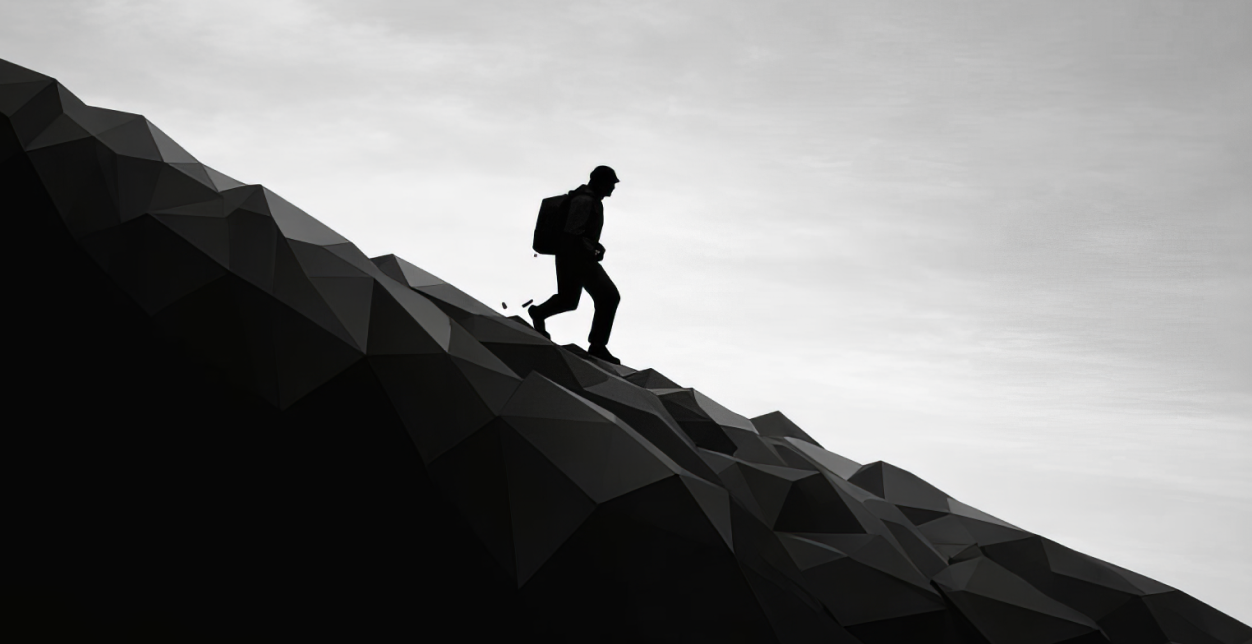 Silhouette of a solitary hiker with a backpack ascending a steep, dark hill against a cloudy sky.