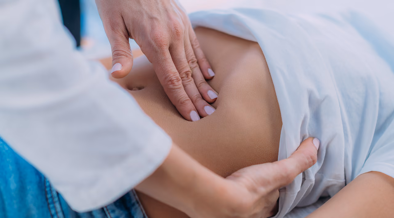 A healthcare professional examines a patient’s abdomen.
