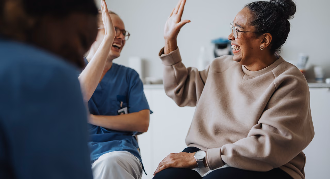 A patient and healthcare professional exchange a high-five during a supportive group session.