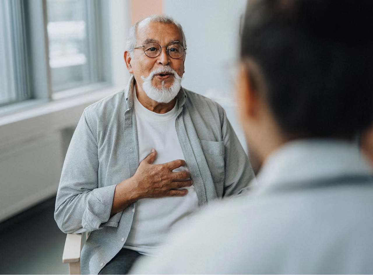 An older man discusses his health with a healthcare professional during an appointment.